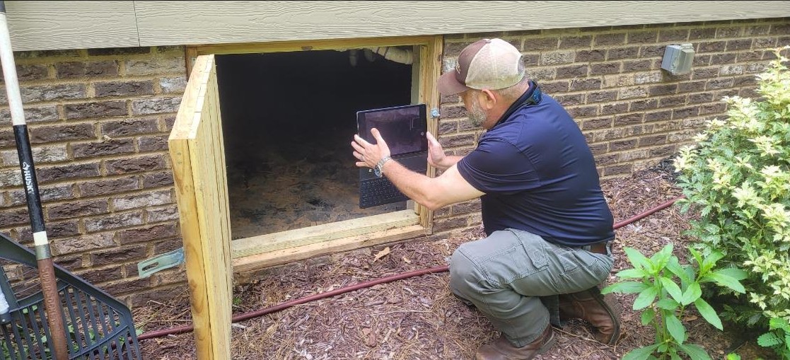 Critter-Ridder wildlife removal specialist documenting conditions at a residential crawlspace